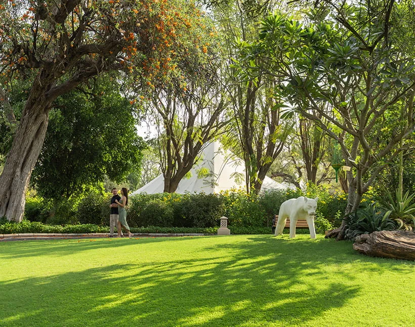 A couple strolls in The Oberoi Sukhvilas, Siswan Forest Resort garden.